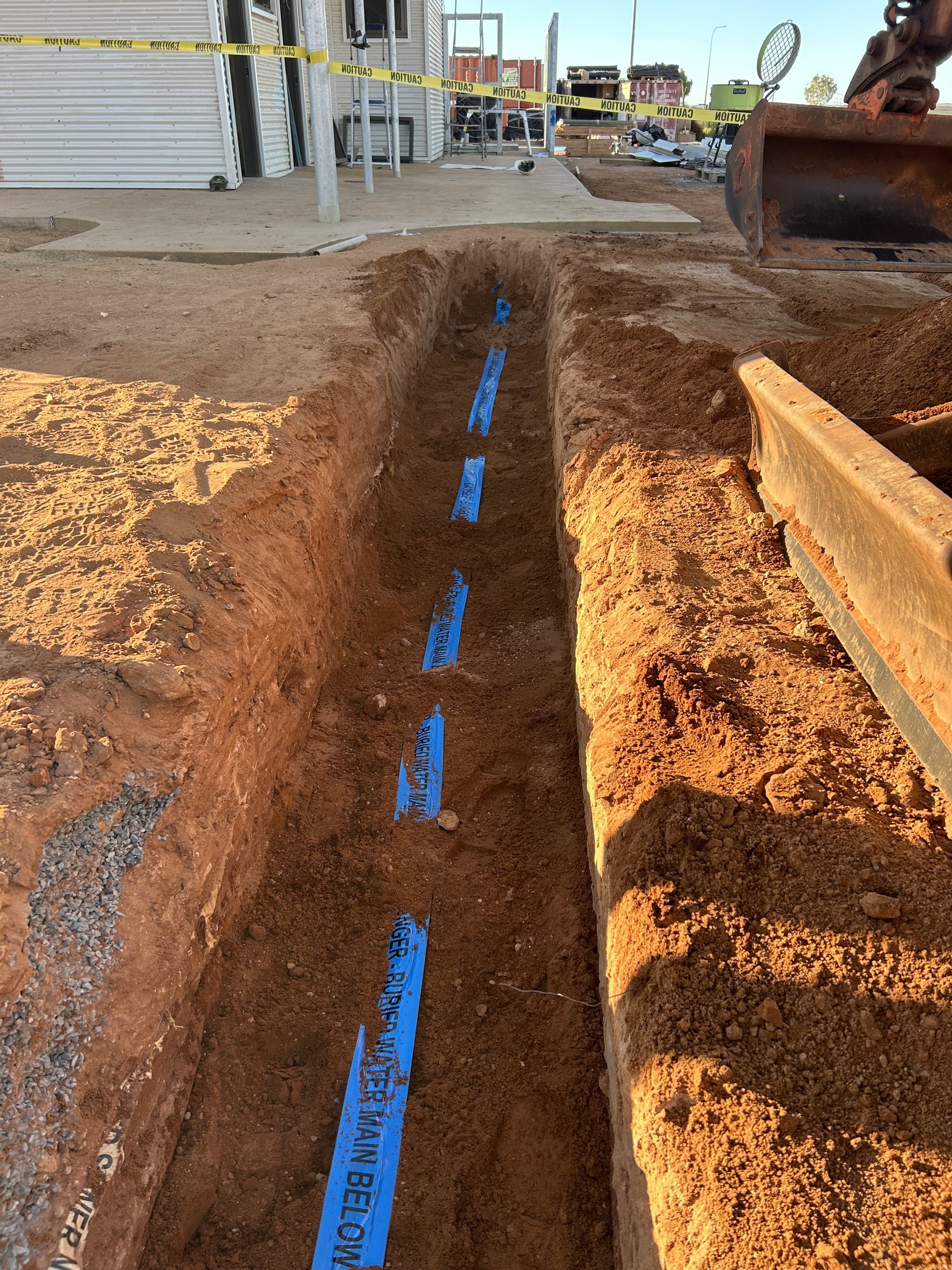 Water main trench with marker tape prior to backfill